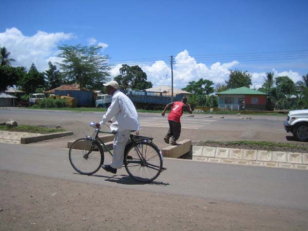 Even better, pedestrian and non-motorized traffic can be kept safely removed from motorized traffic by accessible sidewalks separated from the roadway, in this case by a well-designed drainage system along a main road in Tanzania. Speed bumps are used to slow traffic at crosswalks.