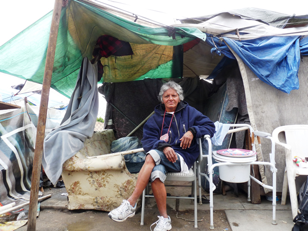 Cynthia proudly sits outside the makeshift home she has constructed on the sidewalk in Fresno, California, a US city with over 3,000 homeless people and less than 300 shelter beds. Photo by Christopher Herring.