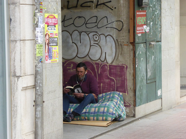 An obviously educated man creates a home for himself in the exterior foyer of an abandoned building in Valencia, Spain.  Photo by Benjamin Clavan, 2015.